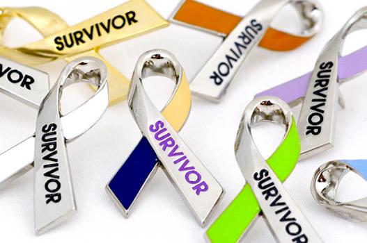 Several cancer awareness ribbon pins,, all with the word "Survivor" on them, in different colors for different types of cancer